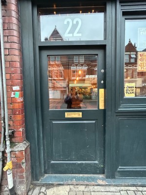 Dark green wooden door with glass panel. Push from right to open.