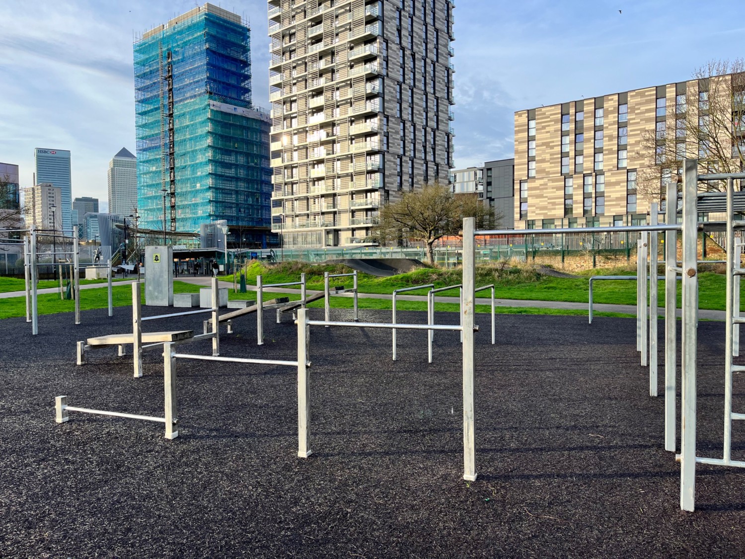 Exercise equipment - bars and benches of varying heights. All is outdoors and open-air. The flooring is rubber safety flooring with a smooth finish.