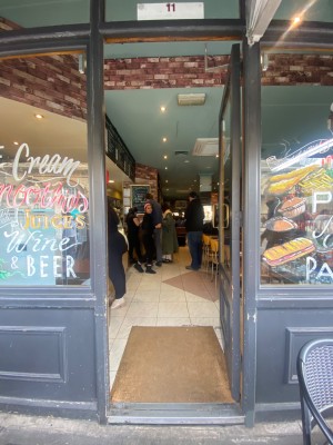 Glass door with grey frame. Push from left to open.