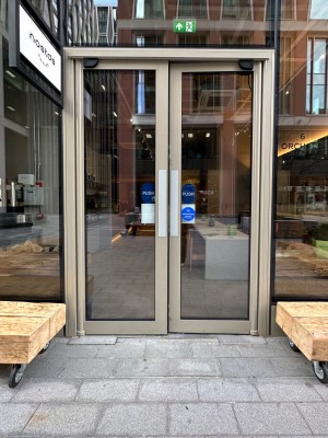 Double glass doors with metal doorframe. Push from the centre to open.