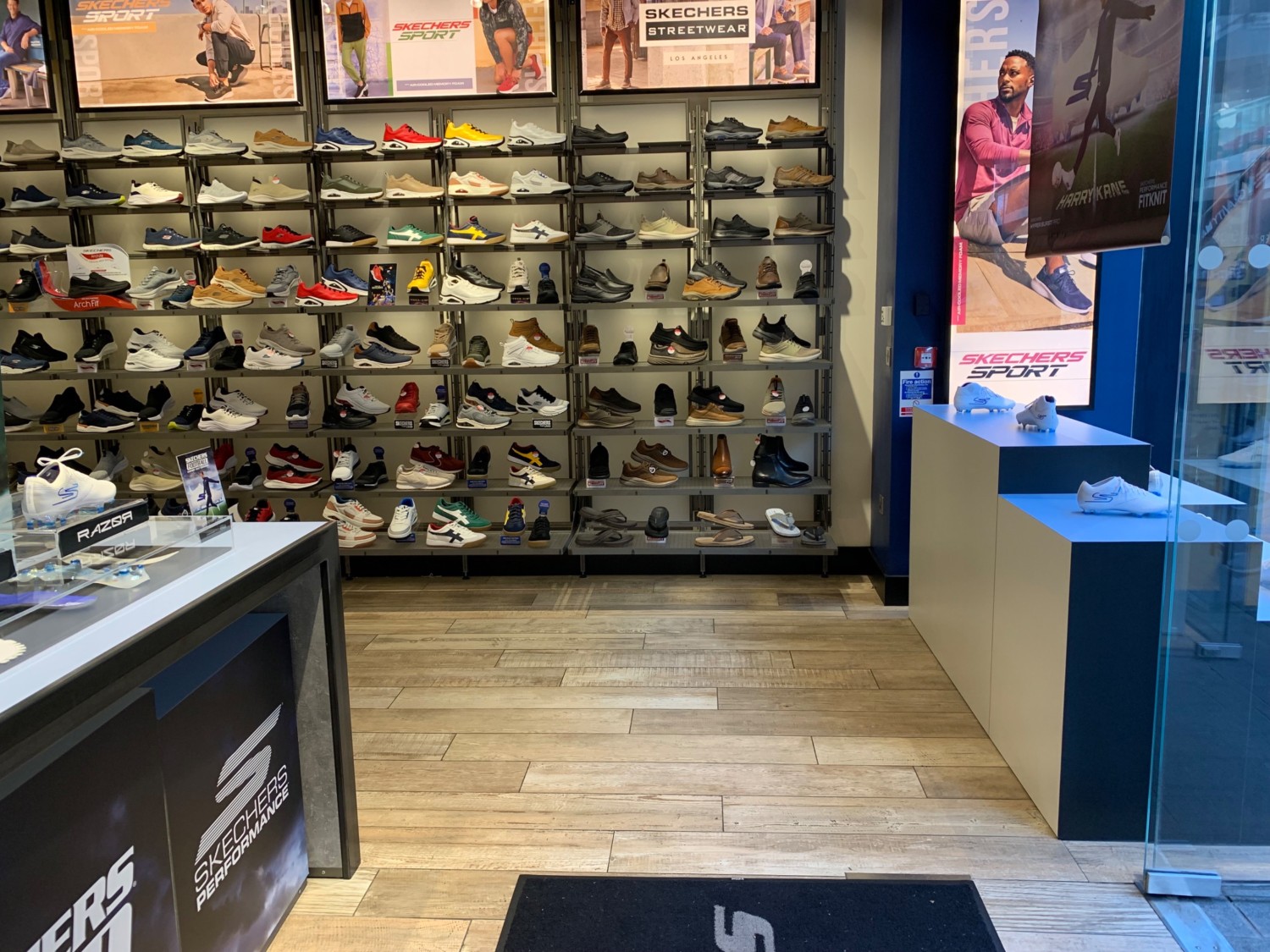 From entrance, facing right. Display table on left. Product shelves along back and right.