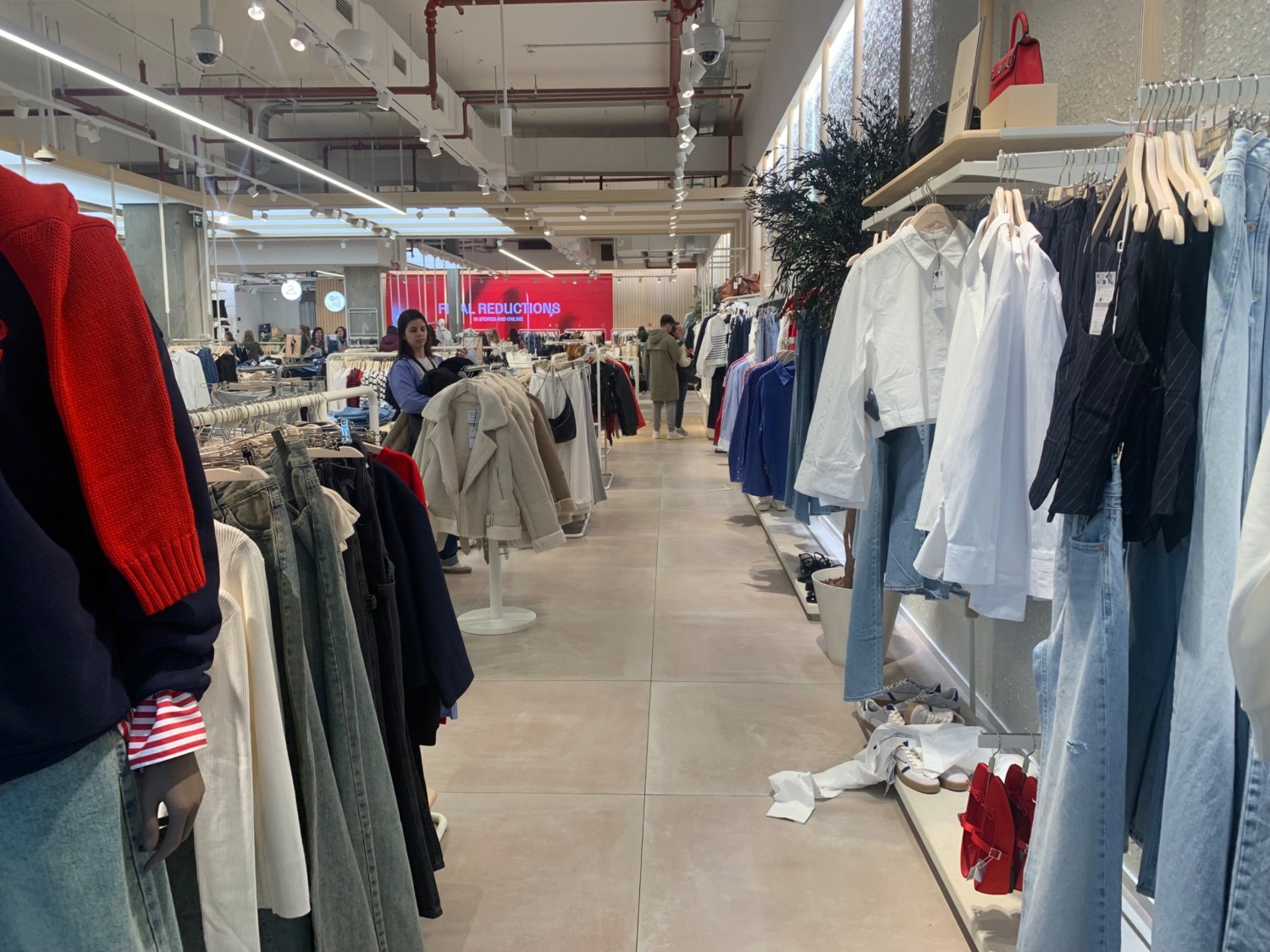 From end of path facing left. Clothing racks along left and right side. Path in centre to more clothing racks.