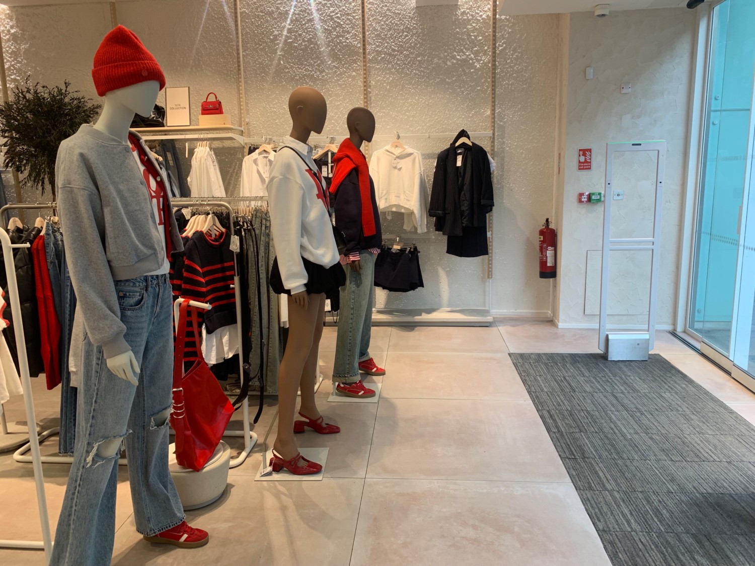From entrance facing right. Mannequins and clothing racks along left. Pathway straight ahead to clothing racks along back wall.
