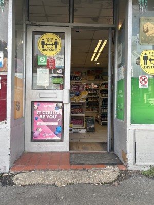 The entrance. The floor is uneven with cracks. Left door is blocked by a freezer, and the hinge of the other sticks out. The right door is kept open.