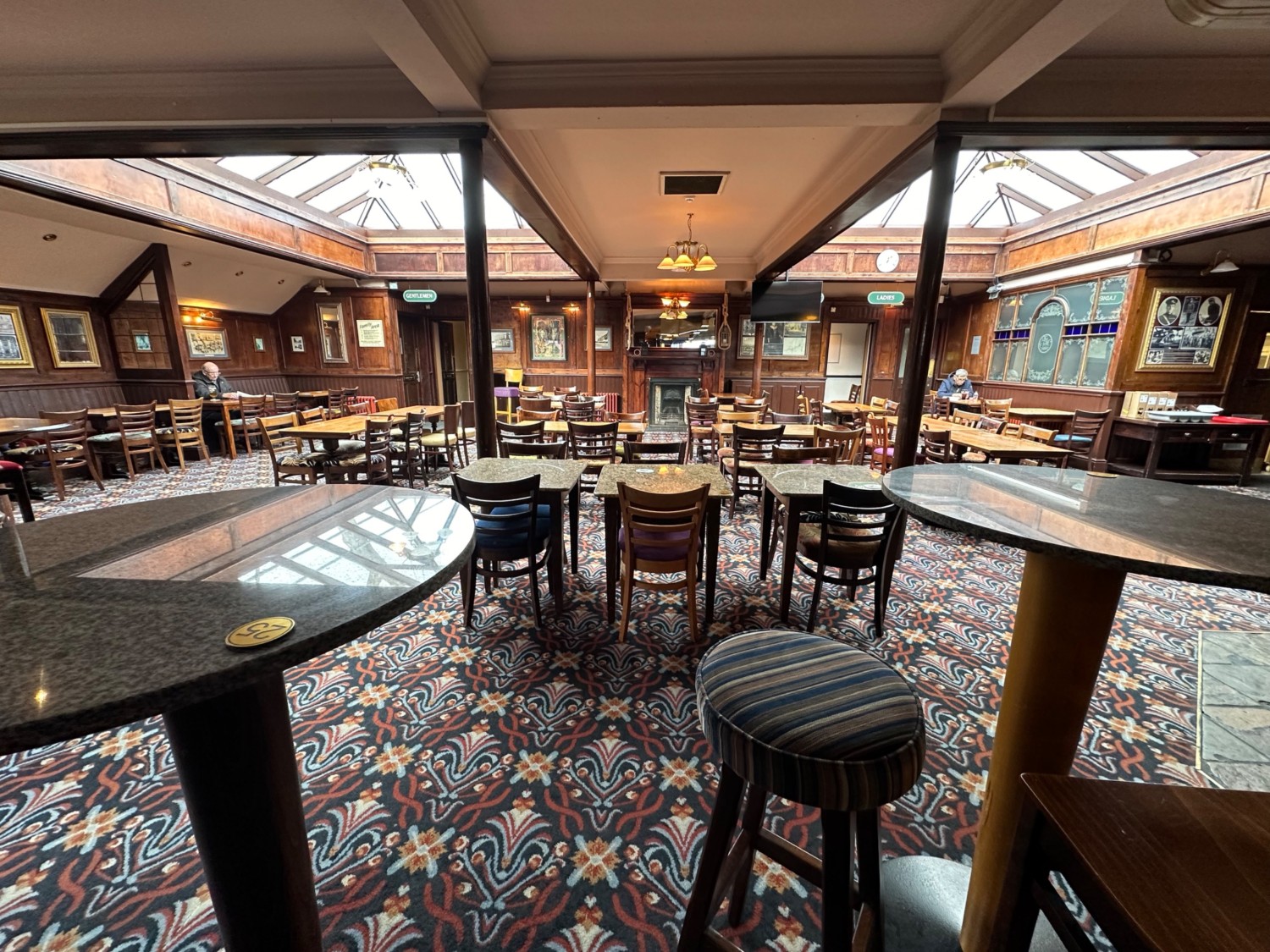 From end of high table facing right. High tables and stools on left and right. Tables and chairs at the back.