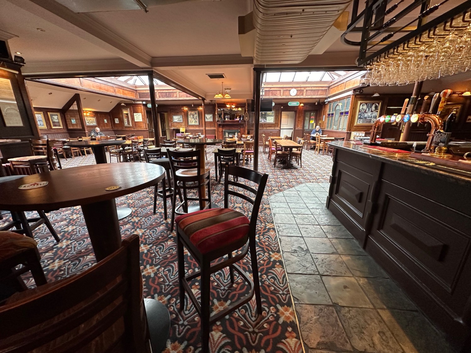 From end of bar facing straight. High tables and stools along left. End of bar on right.