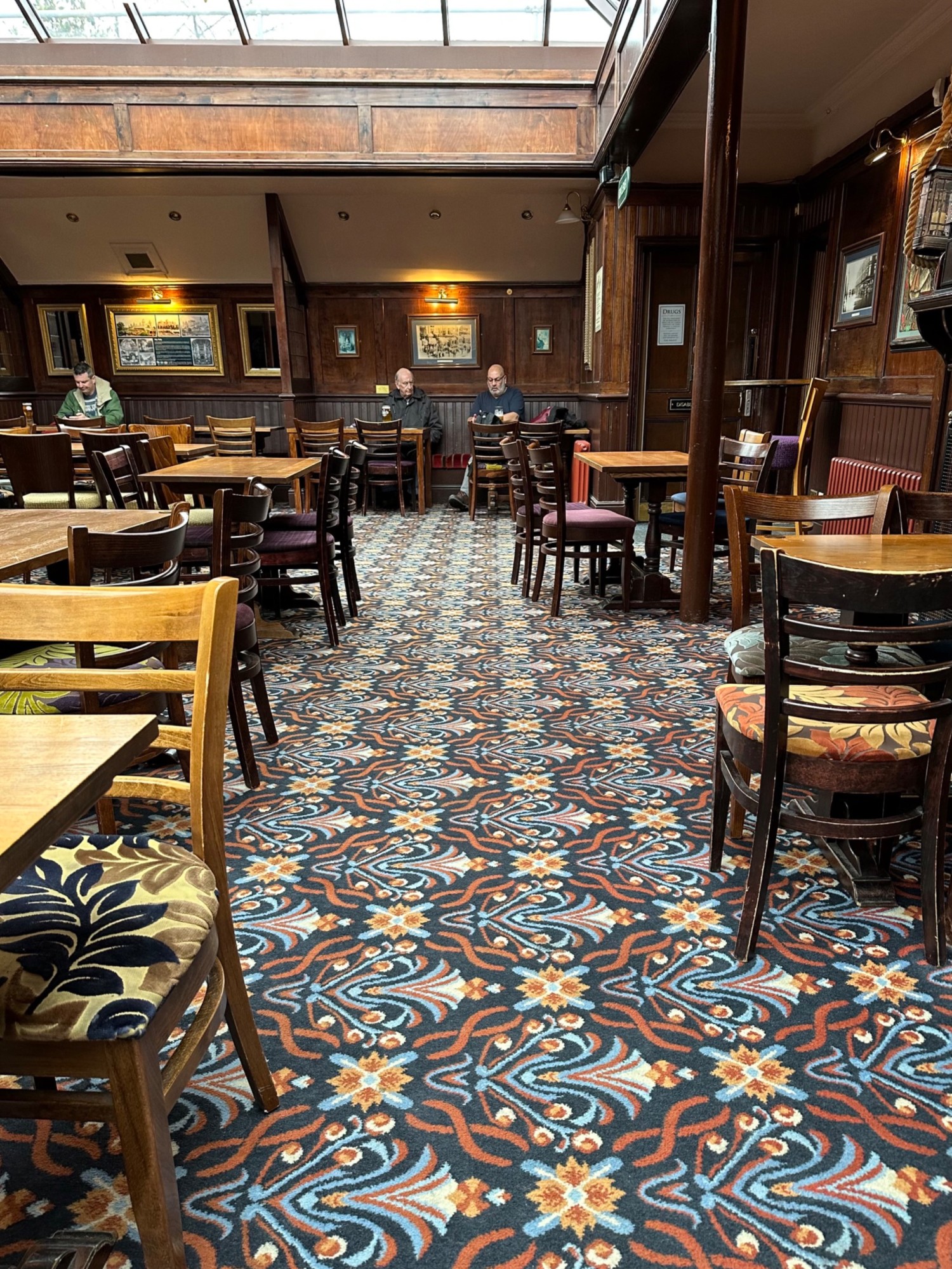 From end of tables facing straight. More tables and chairs along both sides. Half booths on back.