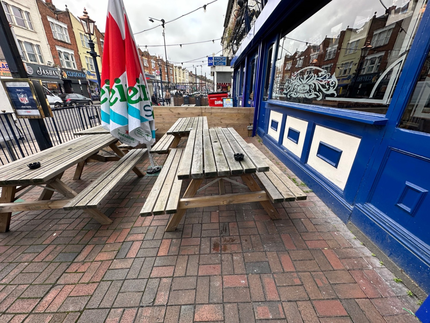 From doors facing right. Two rows of picnic benches ahead. Parasol in-between seating.