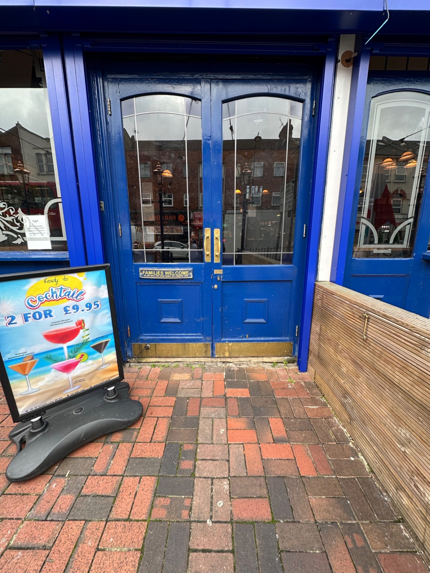 From end of path facing straight. Glass doors with blue frames. Pull from handles in centre to open.