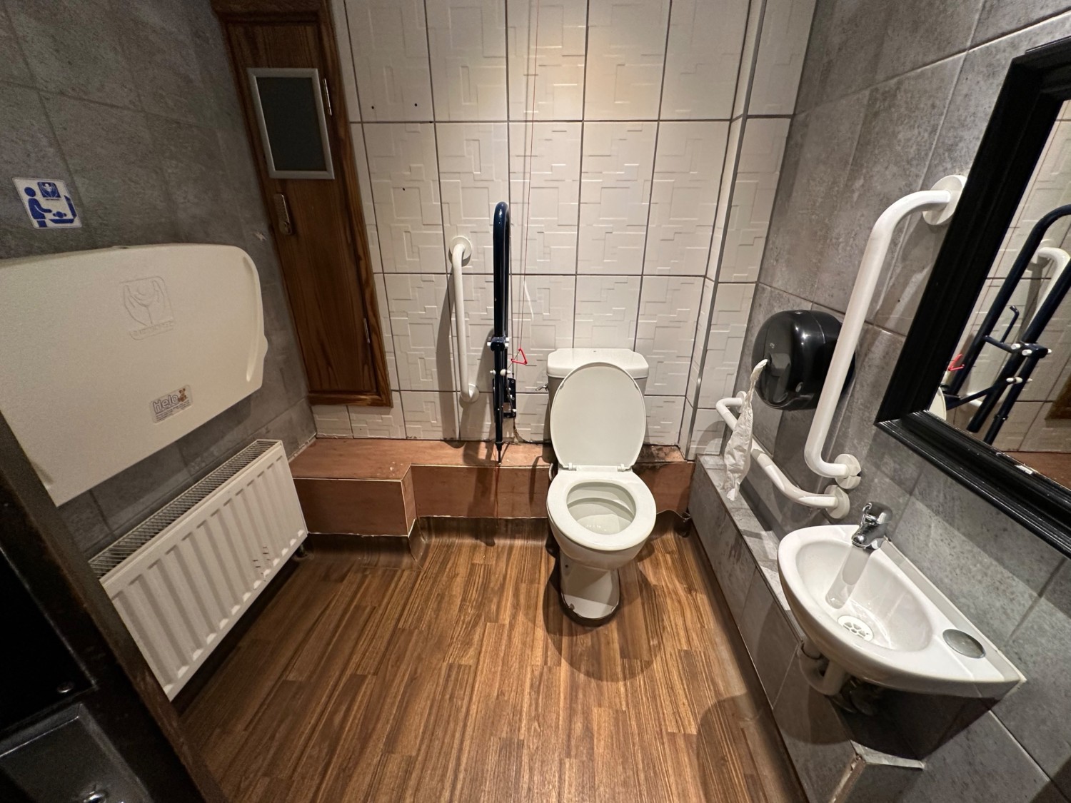From door facing straight. Sink to right. Toilet behind. Emergency cord to its left. Baby change to left.