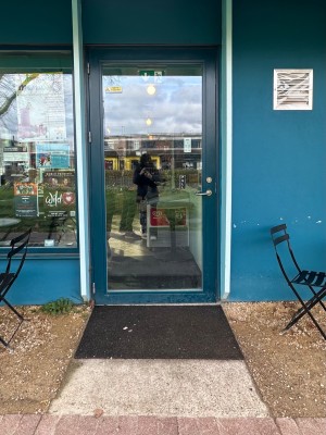 Built in ramp up to glass with blue doorframe. Handle at right. Rotate and pull to open.