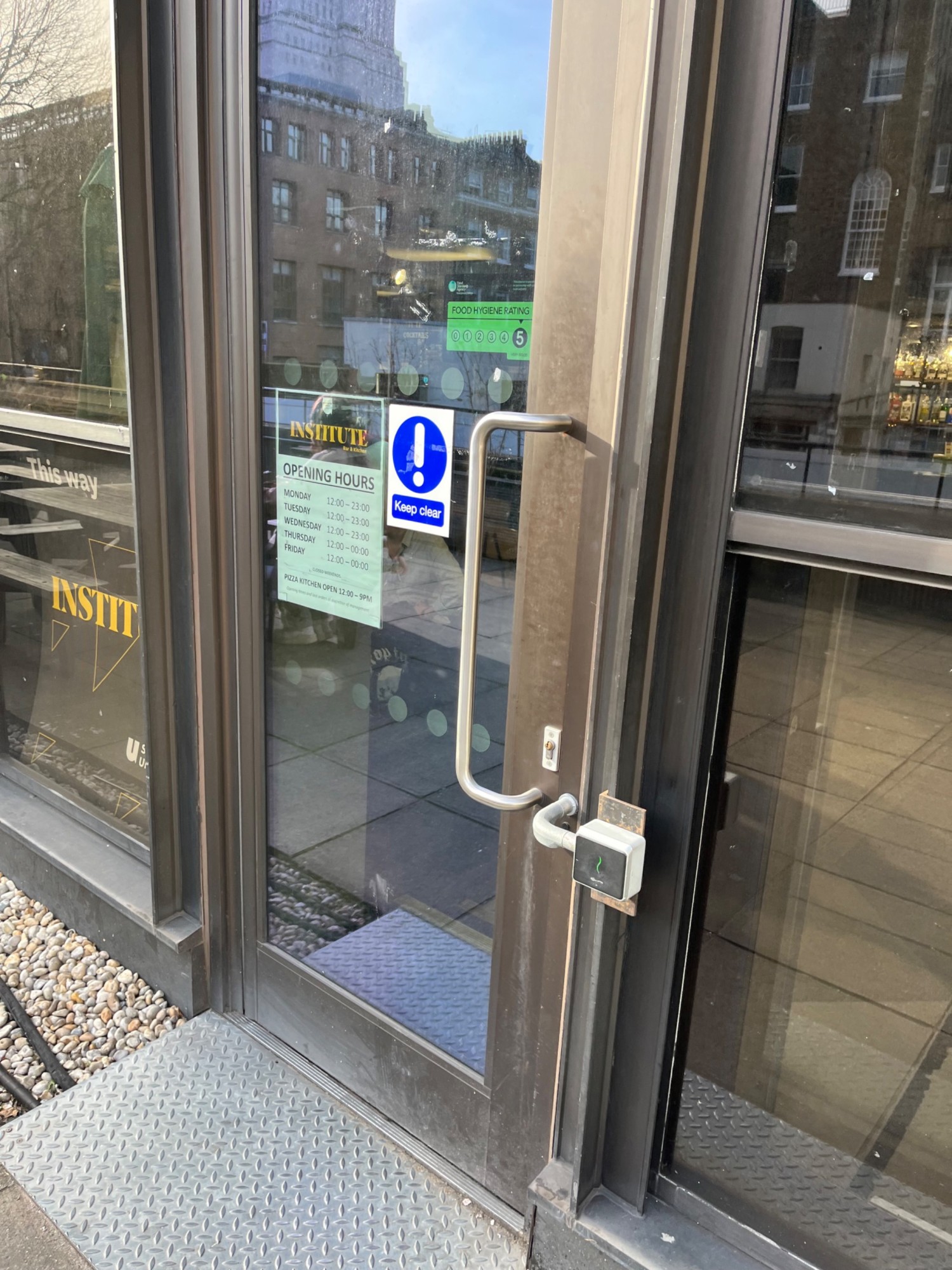 Black framed glass door. Pull from right via long vertical handle to open. Key card pad to low right.