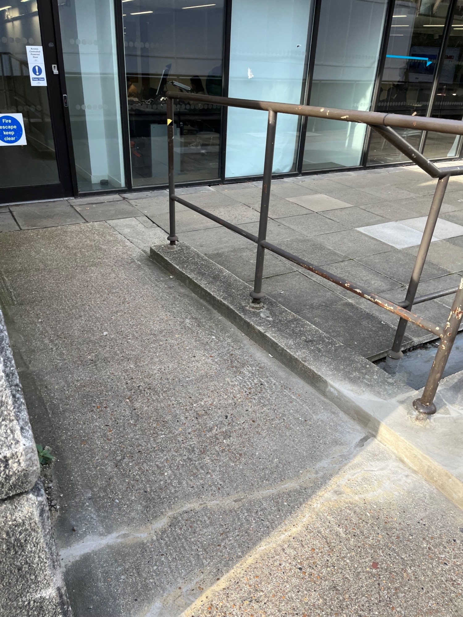 From end of path looking left. Ramp continues up to entrance with handrail to right.