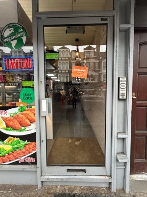 Glass door with grey, metal frame ahead. Push silver handle on left to open.