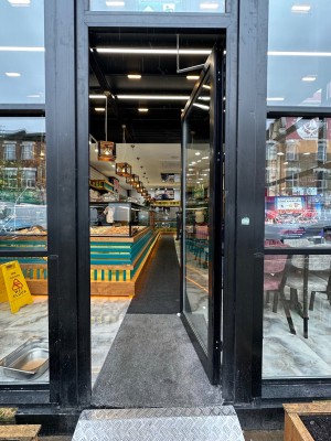 Glass door with black, wooden frame. Push black handle on left to open.