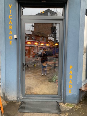 Glass door within grey frame. Push grey handle on left to open.