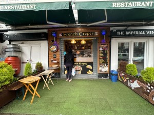 From pavement facing venue. Benches and tables to the left. Counter on back.