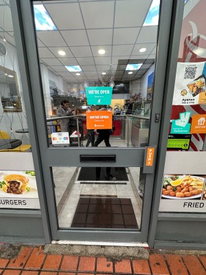 Glass door within grey frame. Push on right to open.