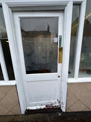 Glass door within white frame. Push on right to open.
