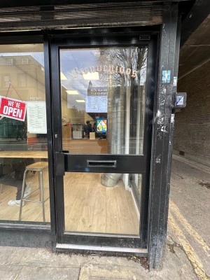 Glass door with black frame. Push black handle from left to open.