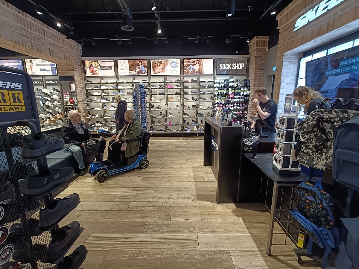 From end of right path, looking left. Product displays on left, stools to their right. Counter along right.