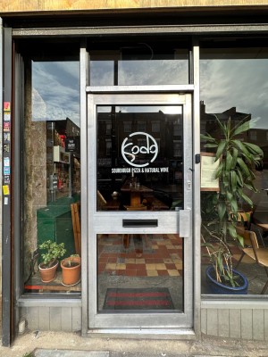 Glass door ahead with metal frame. Push metal handle on right to open.
