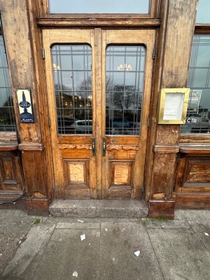 Glass doors within wooden door and doorframe. Pull gold metal handles towards centre to open.