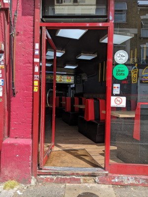 Glass door with red frame and silver handle. Push from right to open.