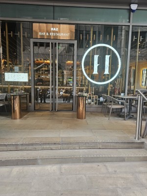 The main entrance of the Haz Restaurant in Fenchurch Street. It has a clear glass double door, but only the left door opens. There is no ramp access.