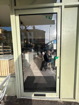 Green framed glass door. Push green handle on right to open.