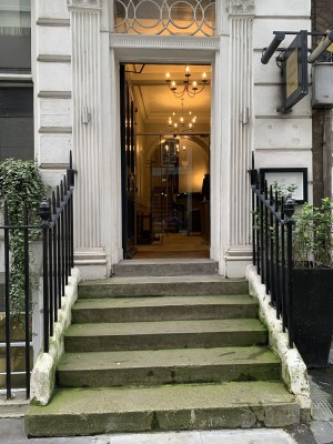 Six steps leading up to an open door and behind that a single glass push door