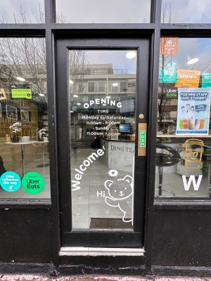 Glass door with black frame. Push from right to open.