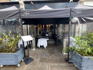 From street facing venue. Path way to main entrance proceeds between to plastic flaps. Menu stand to left.