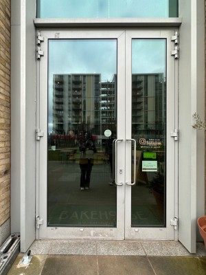 Glass doors with silver doorframe. Pull handle on right to open.