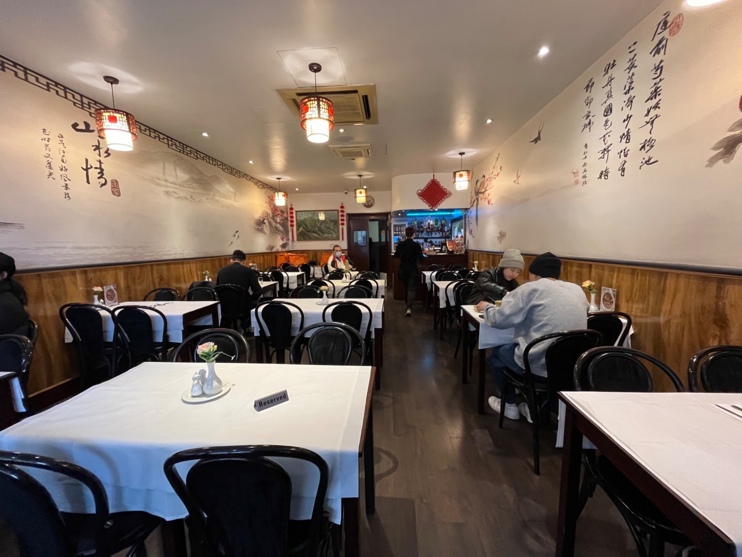 From entrance facing right. Tables and chairs to left and right. Path in centre to counter at back.