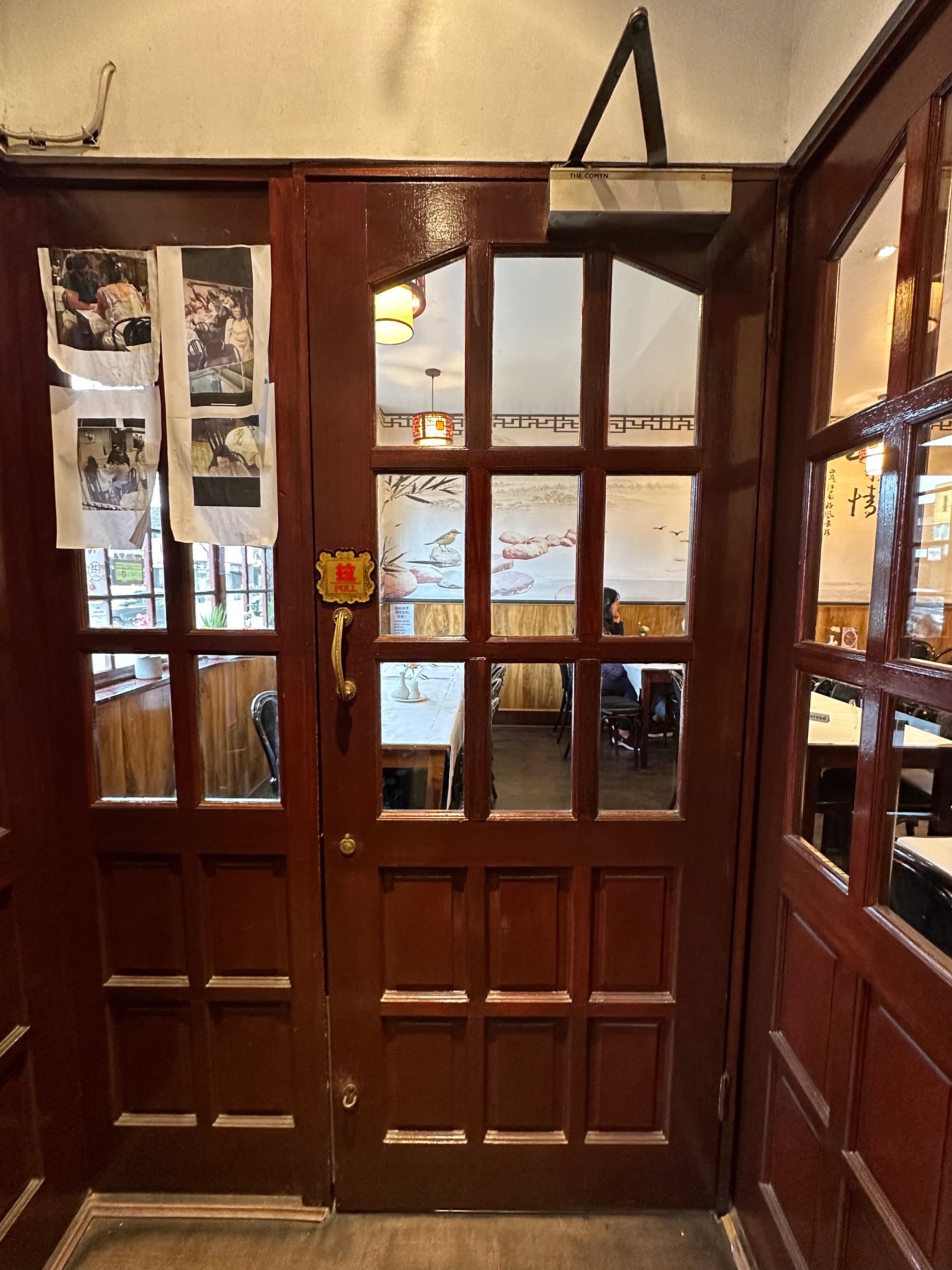 From first set of door facing left, second set of door ahead. Wooden glass paneled door with handle at left. Pull to open.