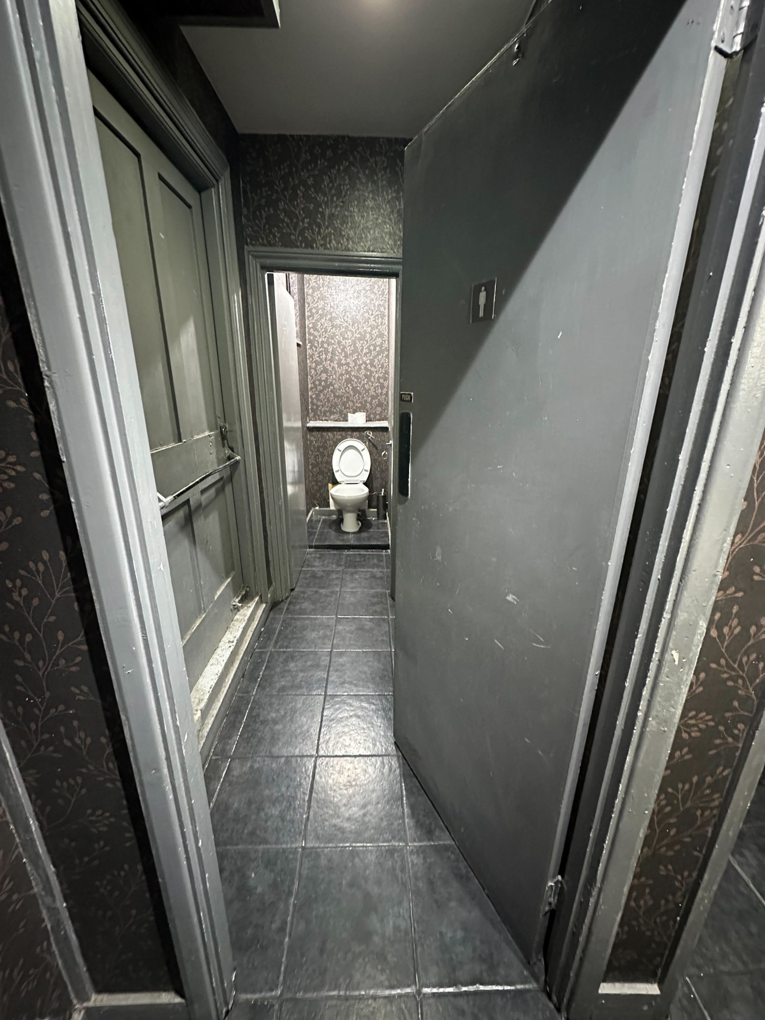 Preceding door to mens toilet. Push from left to open.