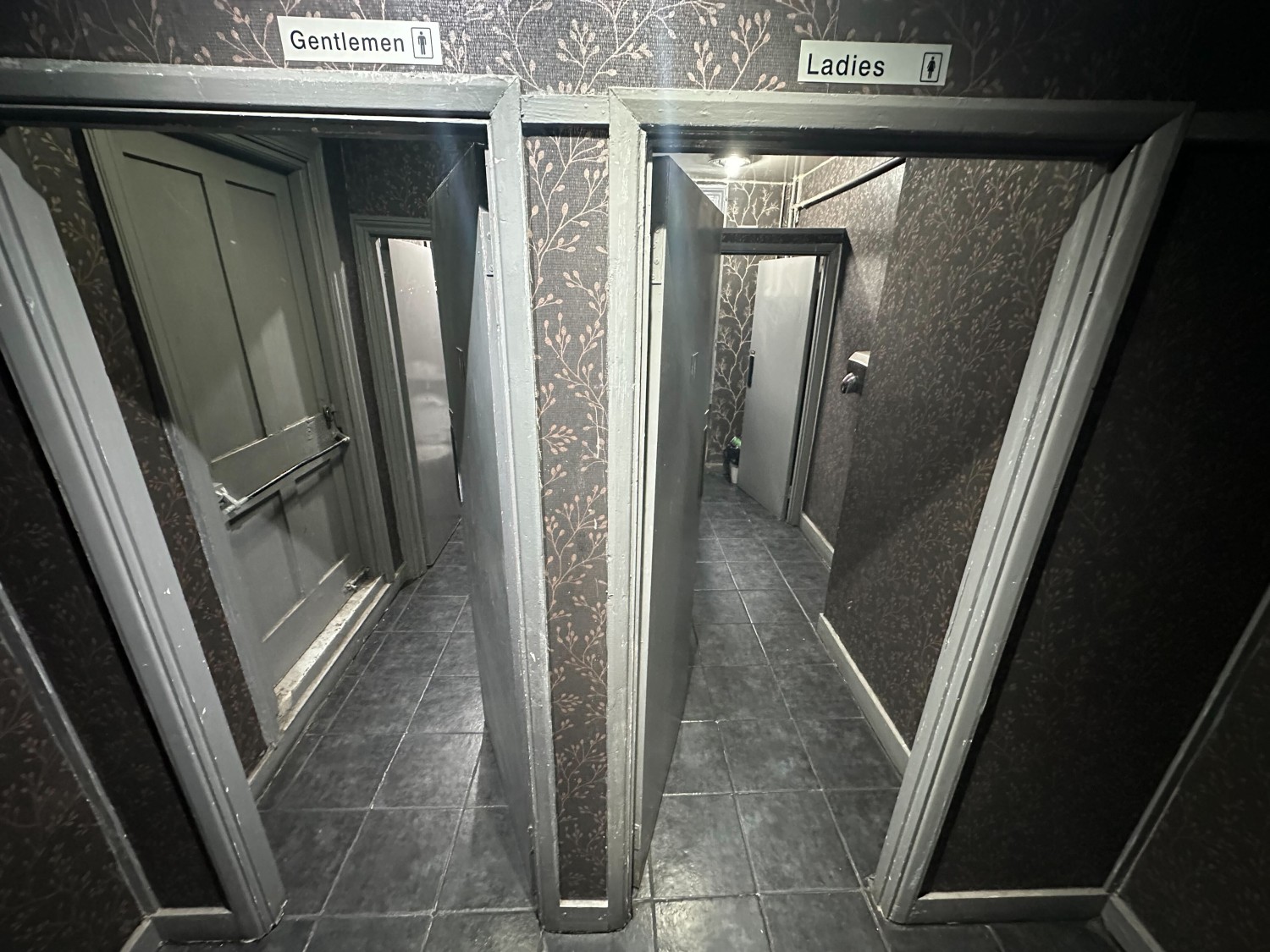From bottom of steps facing straight. Preceding door to toilets along back wall. Mens to left, womens to right.