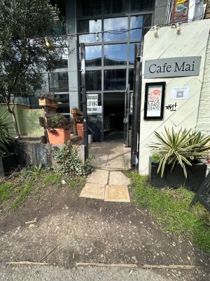 From pavement looking straight. Dirt path leading to concrete paving. First preceding black gate straight ahead.