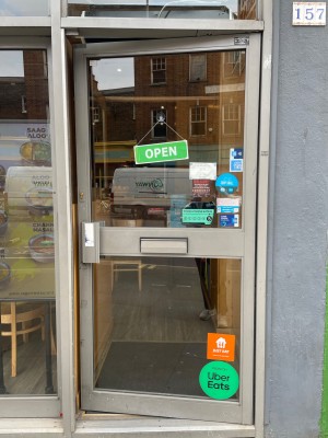 Glass door with grey metal frames ahead. Push from left to open.