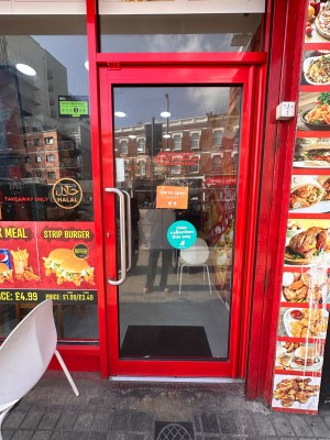 Glass door with red metal frame. Push silver handle on left to open.