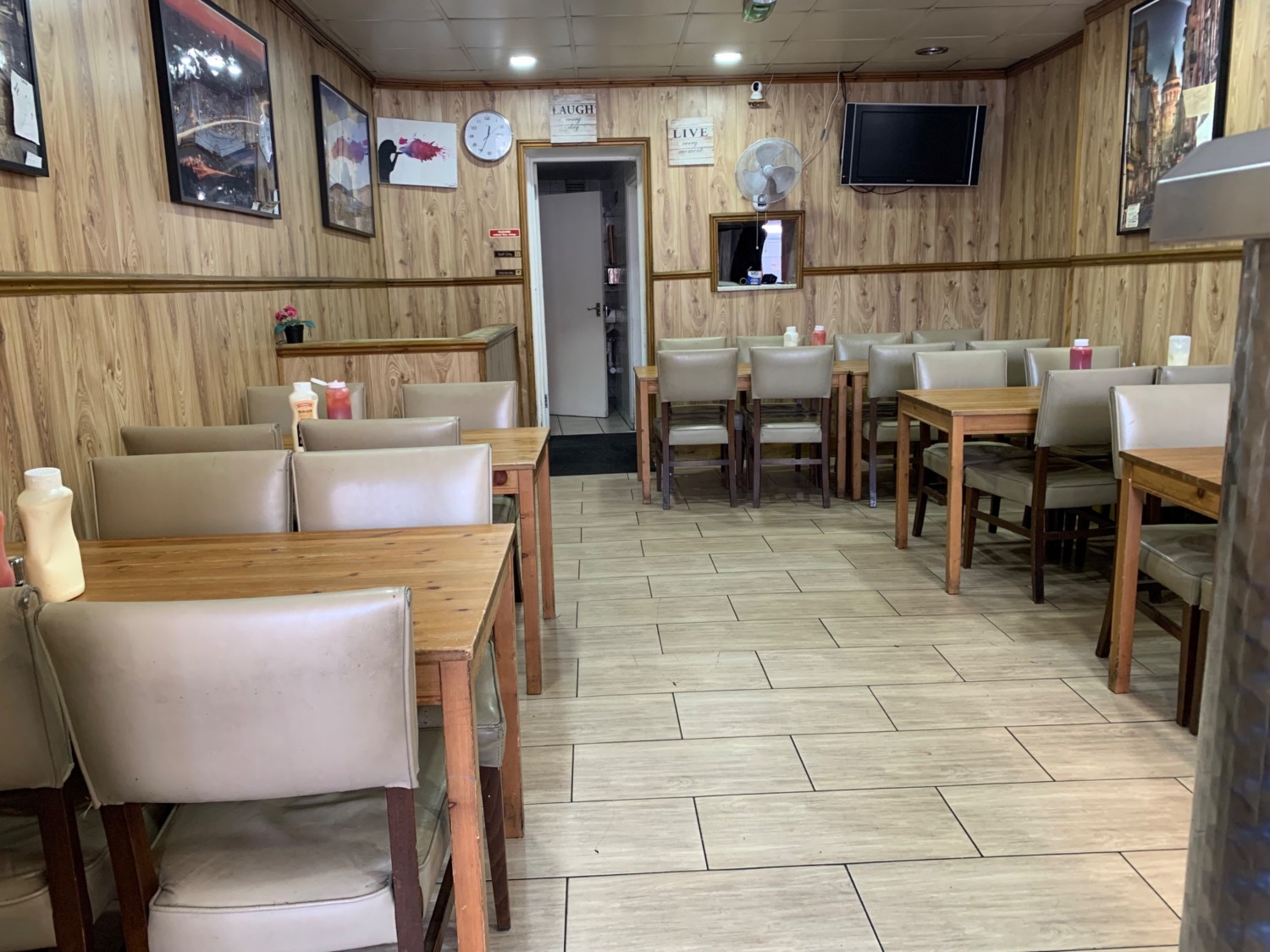 From end of counter facing straight. Tables and chairs along right both sides. Path down center to bathroom on back.