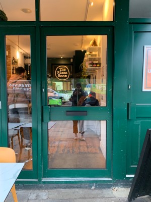 Glass door with green metal frame ahead. Push from handle on left to open.