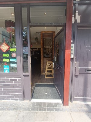 Glass door with brown, metal frame ahead. Push from left to open.