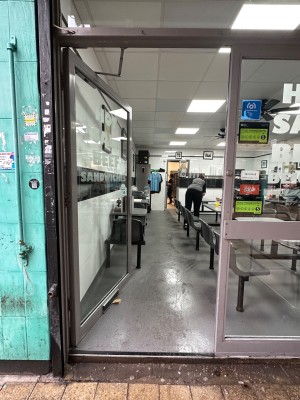 Glass door with gray doorframe. Push handle on right to open.