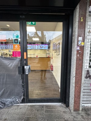 Glass door with black frame. Push black handle on left to open.