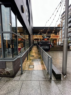 From bottom of built-in ramp looking straight. Silver Handrail on left and right of path ahead.