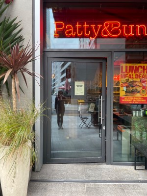 Glass door with grey frame ahead. Push metal handle on right to open.