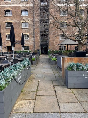 From street, facing venue. Planters along both sides. Path ahead to doorway.