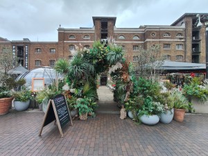 Archway in centre leading to cobblestoned main pathway to entrance. Plants on left and right.